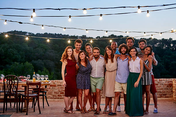 Full length portrait of happy friends standing together at patio during social gathering