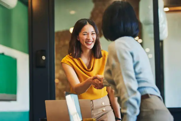 cheerful-businesswomen-shaking-hands-in-meeting-room